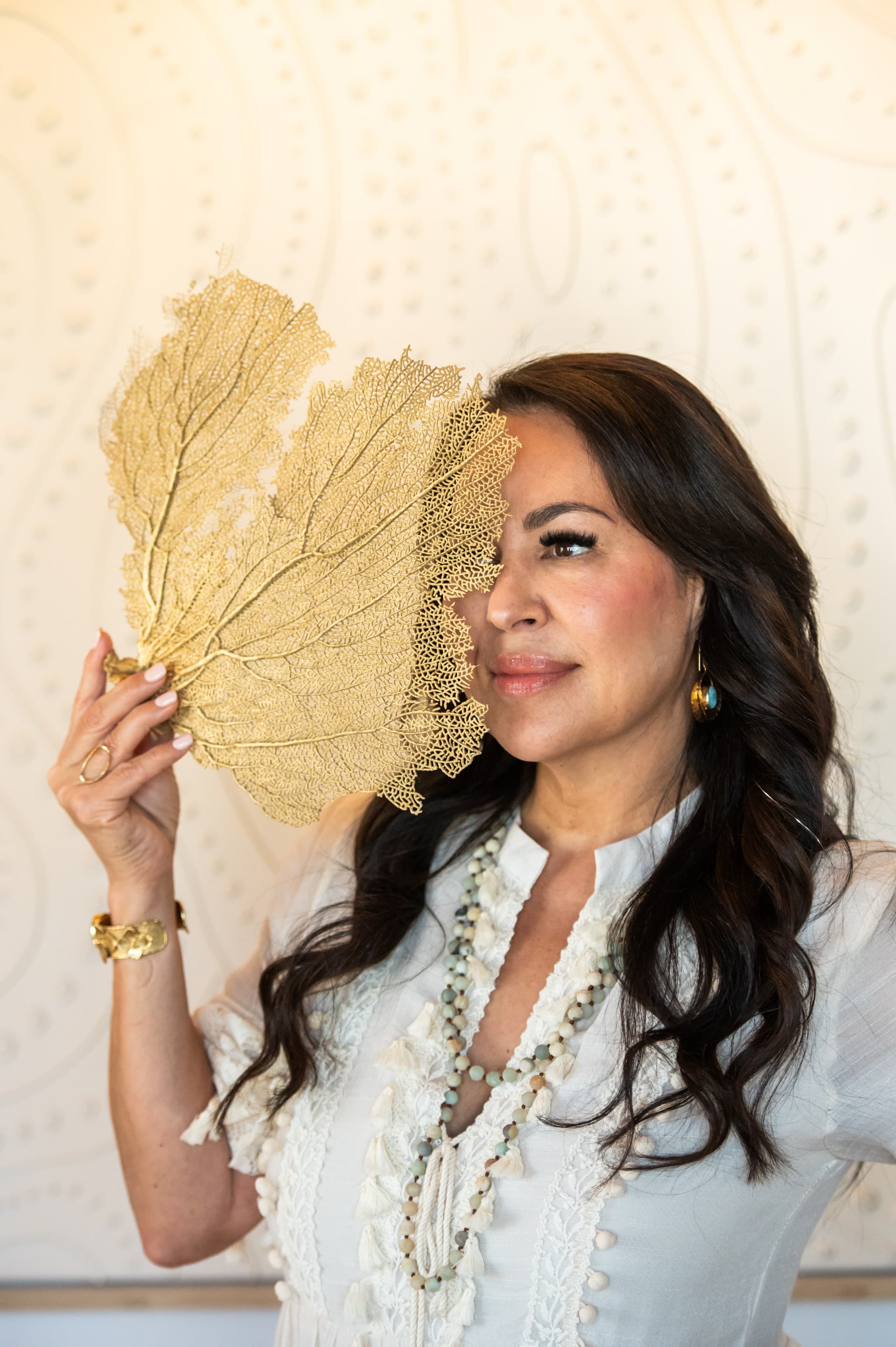 Bex Torres holding a golden sea fan at Siren Beauty + Wellness